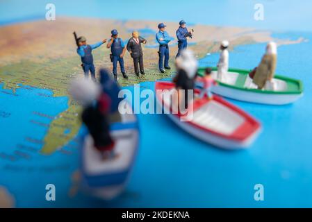 Miniatur-Menschenkonzept der Menschen aus dem Nahen Osten kommen mit dem Boot an die Grenze der USA. Stockfoto