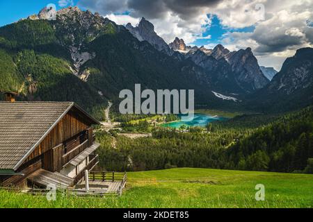 Holzhaus am Hang und schöner türkisfarbener Toblacher See im Hintergrund, Toblach, Dolomiten, Italien, Europa Stockfoto