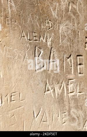 Wand mit Aufschrift darauf. Beschädigt mit verschiedenen Unterschriften in seiner weichen Schicht geschnitzt. Stockfoto