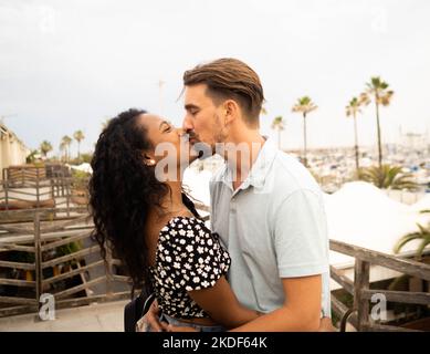 Heterosexuell verschiedenes junges Paar, das sich während eines Urlaubs küsst. Liebe, Flitterwochen Stockfoto