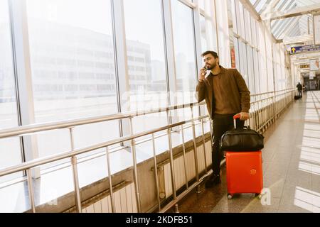 Indischer bärtiger Mann, der sich im Bahnhof im Haus mit dem Handy unterhielt Stockfoto