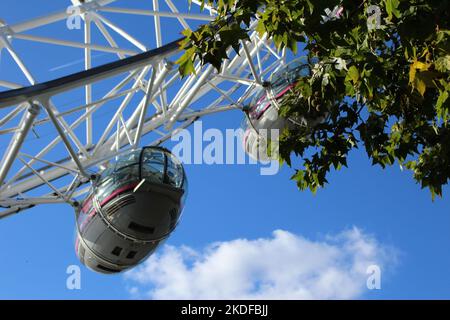 Touristen genießen das Millennium Wheel an einem sonnigen Tag. Nahaufnahme der Kutschen auf dem London Eye mit Grün und blauem Himmel Hintergrund. Stockfoto