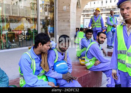 KATAR, Doha, Musheireb, Bauboom für FIFA Fußball WM 2022, der Bau wird von Wanderarbeitern aus aller Welt durchgeführt, Mittagspause unterwegs / KATAR, Doha, Bauboom fuer die FIFA Fußball WM 2022 / KATAR, Doha, Bauboom fuer die FIFA Fußball WM 2022, Abrissviertel Musheireb, auf den Baustellen für Neubauten schufen Gastarbeiter aus aller Welt, Workers at Mittagspause auf der Strasse Stockfoto