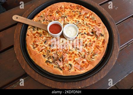 Pizza serviert mit Schinken, Pilzen und Mozzarella-Käse Stockfoto