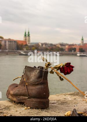 Schuh am Donauufer mit Blumen in Budapest. Gedenkstätte für Opfer des jüdischen Holocaust während des Zweiten Weltkriegs in Budapest, Ungarn. Stockfoto