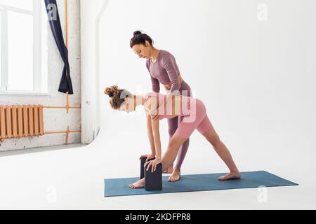 Der Trainer hilft dem Schüler, die Variation der parshvottanasana-Übung, die tiefe Dehnung Pose, die sie im Studio trainieren richtig durchzuführen Stockfoto