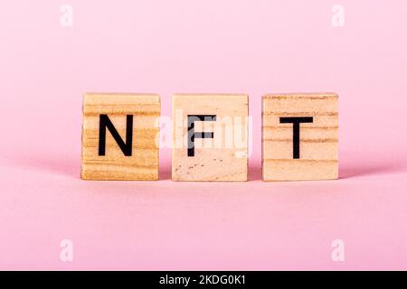 NFT nicht fungible Token-Text auf rosa Hintergrund. Krypto-Kunstkonzept. Technologie, die einzigartige Sammlerstücke, Spielfiguren, Blockchain-Assets und verkauft Stockfoto