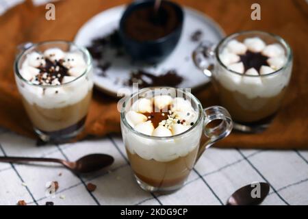 Kleine Tassen mit einem dreischichtigen Kaffee-Karamell-Dessert. Köstlicher Pudding in Glasbechern. Stockfoto