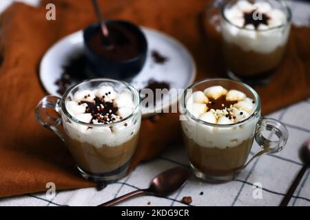 Kleine Tassen mit einem dreischichtigen Kaffee-Karamell-Dessert. Köstlicher Pudding in Glasbechern. Stockfoto