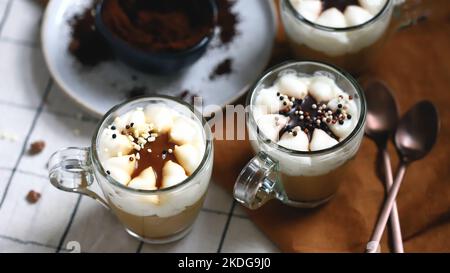 Kleine Tassen mit einem dreischichtigen Kaffee-Karamell-Dessert. Köstlicher Pudding in Glasbechern. Stockfoto