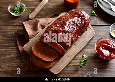 Hackbraten mit Glasur auf Schneidebrett auf Holzhintergrund. Nahaufnahme Stockfoto