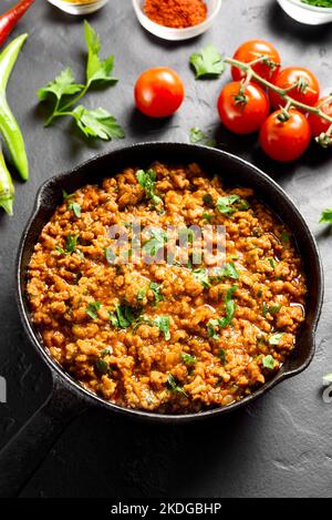 Keema-Kerk in gusseiserner Pfanne auf schwarzem Steingrund. Indische und pakistanische Gerichte. Stockfoto