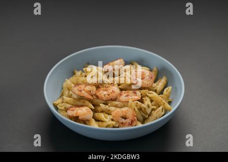 Penne mit Garnelen und Pesto in blauer Schale, flacher Fokus Stockfoto