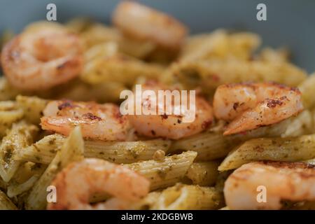 Penne mit Garnelen und Pesto in blauer Schale, flacher Fokus Stockfoto