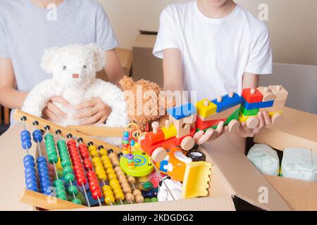 Junge Freiwillige sammeln Spendenbox mit Kleidung, Schulbedarf, Kinderspielzeug, Essen. Spenden, Wohltätigkeitsorganisationen, Nahrungsmittelbanken, Hilfe für Familien mit niedrigem Einkommen Stockfoto