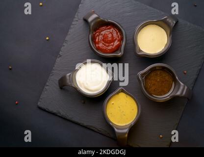 Verschiedene Saucen auf schwarzem Hintergrund Stockfoto