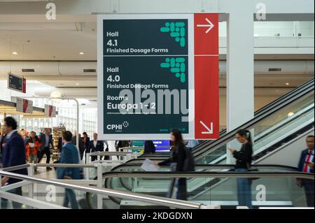 Besucher auf der Fahrtreppe, die an Wegweisern auf der CHPI 2022 in der Messe Frankfurt vorbeifährt Stockfoto