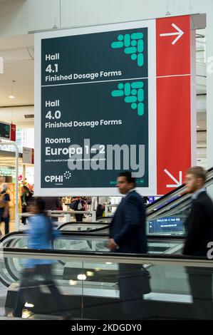 Besucher auf der Fahrtreppe, die an Wegweisern auf der CHPI 2022 in der Messe Frankfurt vorbeifährt Stockfoto