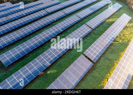 Eine Luftaufnahme von Reihen von Photovoltaik-Solarmodulen, die bei Sonnenaufgang sauberen und erneuerbaren Strom auf landwirtschaftlichem Ackerland im Vereinigten Königreich erzeugen Stockfoto