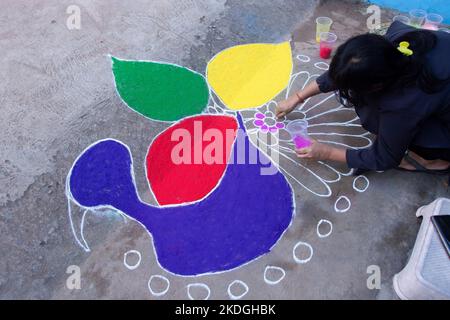 Stammesvolk, das am Vorabend von Diwali Rrangoli zieht Stockfoto