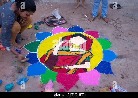 Stammesvolk, das am Vorabend von Diwali Rrangoli zieht Stockfoto