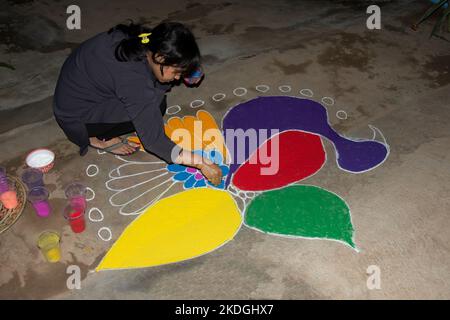 Stammesvolk, das am Vorabend von Diwali Rrangoli zieht Stockfoto