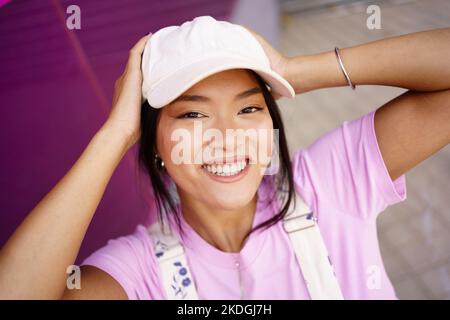 Asiatische Frau berührt den Kopf und lächelt Stockfoto