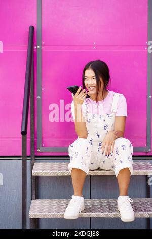 Asiatische Frau sendet Sprachnachricht Stockfoto