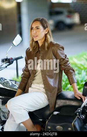 Stilvolle Frau sitzt auf dem Motorrad Stockfoto