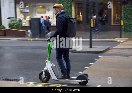 Intelligenter junger Mann, der auf einem Lime + Uber Elektroroller in Regent Street Westminster London West End reitet Stockfoto