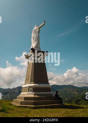 Jerico, Antioquia, Kolumbien - April 4 2022: Hohe weiße Statue von Jesus Christus auf einem Hügel gegen den blauen Himmel Stockfoto