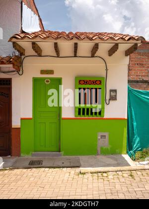 Jerico, Antioquia, Kolumbien - April 5 2022: Weißes, winziges Haus im Kolonialstil mit grün lackierten Holztüren und Fenstern Stockfoto