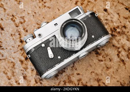 Alte Vintage-Filmkamera auf dem Tisch. Retro-Fotokamera mit silber-schwarzem Gehäuse. Klassische analoge Fotokamera. Stockfoto