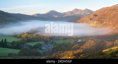 Der Nebel, der über Llynnaus Mymbyr hängt, verschiebt sich und dehnt das erste direkte Morgenlicht aus, wobei das Sowdon Horseshoe das Tal unter sich dominiert. Stockfoto