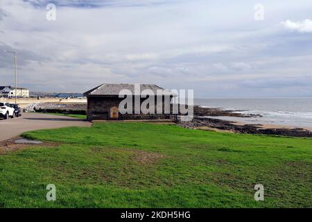 Grauer Steinschutz mit Schieferdach, in der Nähe des Porthcawl Strandes auf der grasbewachsenen Landzunge mit Blick auf Porthcawl. Oktober 2022. Herbst. Stockfoto