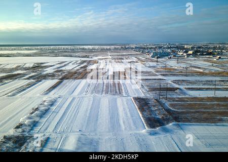 Luftaufnahme von schneebedeckten landwirtschaftlichen Feldern mit karger Oberfläche im Winter Stockfoto