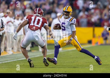 Der LSU Tigers Quarterback Jayden Daniels (5) trägt den Ball, als Henry To'Oto'o (10), der Alabama Crimson Tide-Linienhalter, ihn aus dem Seitenrand drängt Stockfoto