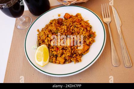 Fleischpaella mit Zitrone auf weißem Teller Stockfoto