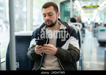 Bärtiger Mann, der im Stadtbus unterwegs war und ein Handy benutzte Stockfoto