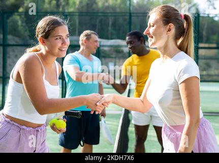 Zwei Frauen schütteln sich die Hände, nachdem sie auf dem Tennisplatz im Freien Padel gespielt haben Stockfoto