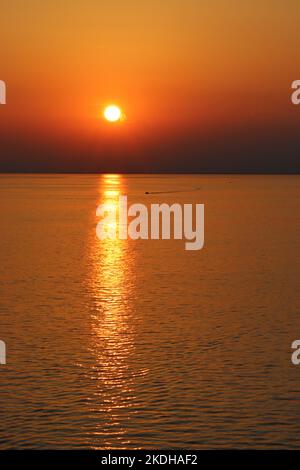 Ein einköpfig starres, aufblasbares Boot erzeugt einen Wachbogen, während es bei Sonnenuntergang zum sicheren Hafen von Triest zurückkehrt Stockfoto