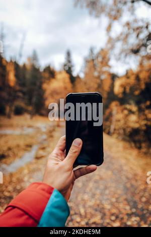 Mann, der mit dem Smartphone eine herbstliche Landschaft fotografiert Stockfoto