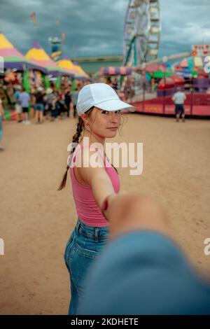 Teen Mädchen führt einen Freund zu Riesenrad an Karneval Stockfoto