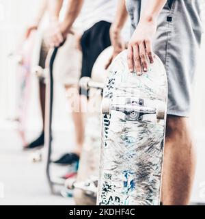 Junge Skateboarder Skateboarding auf der Straße. Eine Gruppe von Freunden, die in einer Reihe mit Skateboards in den Händen stehen. Urbanes Leben. Subkultur der Jugend. Stockfoto