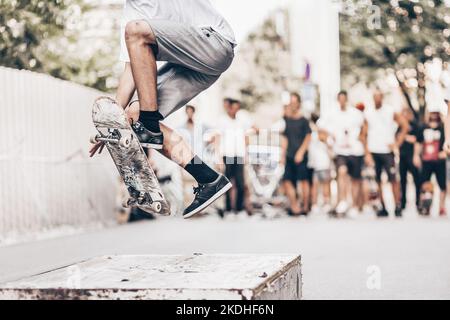 Junge skateboarder Skaten auf ein Objekt in der Straße. Skateboarding Beine tun Trick ollie Am Skatepark. Eine Gruppe von Freunden, die im Hintergrund jubelt. Stockfoto