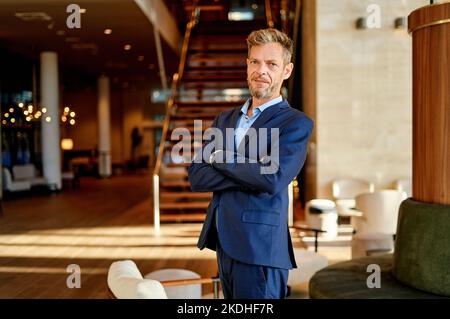 Porträt eines Geschäftsmannes mit gekreuzten Armen, der am Arbeitsplatz posiert Stockfoto