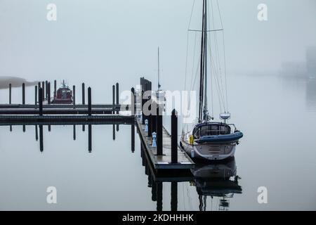 NORWALK, CT, USA - 4. NOVEMBER 2022: Morgennebel auf dem Norwalk-Fluss mit Booten und Reflexion Stockfoto