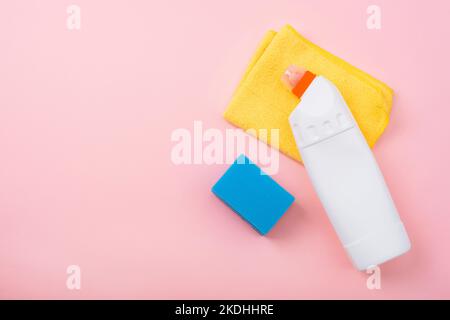 Hausreinigungskonzept, Hausreinigung, Hygiene, Hausarbeiten, Reinigungsbedarf. Reinigungsmittel, gelber Lappen und blauer Schwamm auf rosa Hintergrund. Draufsicht, FLA Stockfoto