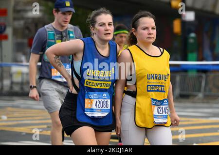 New York, USA. 6.. November 2022. Die Läuferinnen Olga Boiaryntseva (L) und Kateryina Boiaryntseva aus der Ukraine laufen mit Westen in den nationalen Gelb- und Blautönen mit der Aufschrift „Besatzungsstädte“ während des TCS New York City Marathon. Kredit: Enrique Shore/Alamy Live Nachrichten Stockfoto