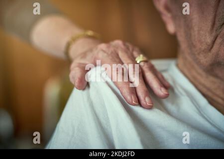 Wahre Freunde bleiben bis zum Ende bei Ihnen. Eine nicht identifizierbare ältere Frau berührt ihren Mann in einem Altersheim auf der Schulter. Stockfoto